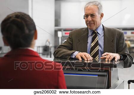 Businessman at a ticket counter in an airport View Large Photo Image Stock Image - Businessman at a ticket counter in an airport. Fotosearch