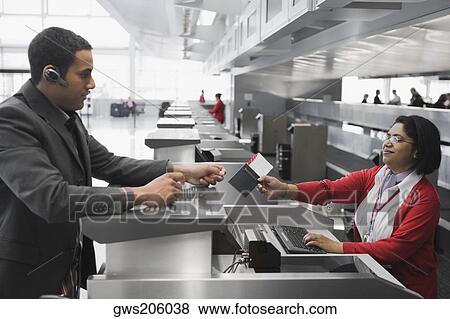 Businessman collecting his passport with an airplane ticket from the airline check-in attendant View Large Photo Image Stock Photo - Businessman collecting his passport with an airplane ticket from the airline check-in attendant. Fotosearch
