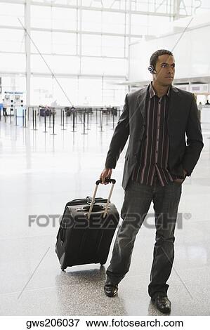 Businessman pulling his luggage at an airport View Large Photo Image Stock Photo - Businessman pulling his luggage at an airport. Fotosearch