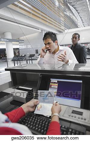 Stock Photography - Businessman shouting in a mobile phone at a ticket counter in an airport. Fotosearch