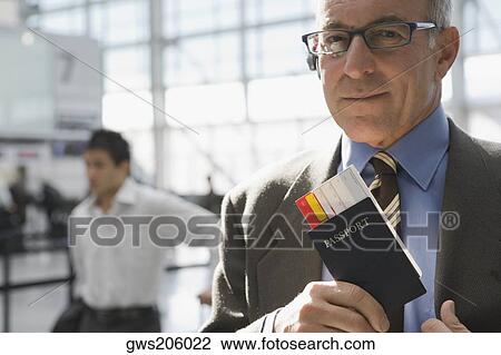 Stock Image - Close-up of a businessman putting a passport with an airplane ticket in his coat's pocket. Fotosearch