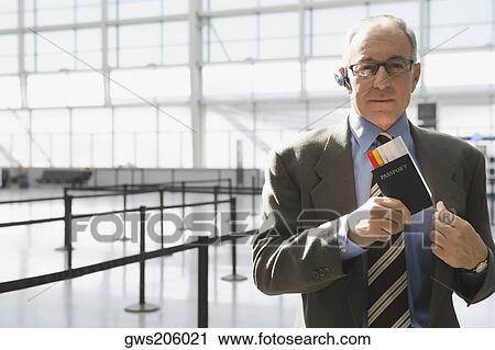 Portrait of a businessman putting a passport with an airplane ticket in his coat's pocket View Large Photo Image Stock Image - Portrait of a businessman putting a passport with an airplane ticket in his coat's pocket. Fotosearch