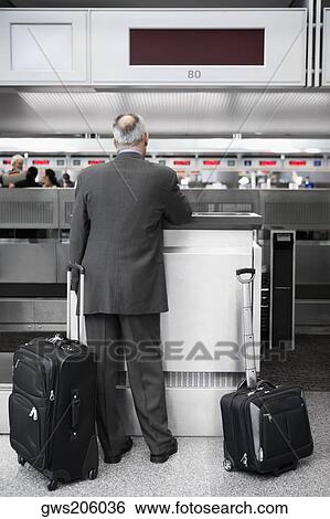Rear view of a businessman standing at a ticket counter in an airport View Large Photo Image Stock Photograph - Rear view of a businessman standing at a ticket counter in an airport. Fotosearch