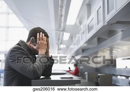 Stock Photograph - Side profile of a businessman looking serious at a ticket counter in an airport. Fotosearch