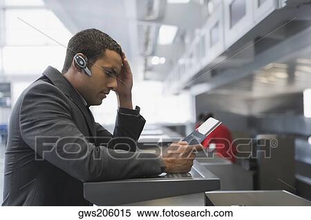 Stock Photography - Side profile of a businessman looking serious at a ticket counter in an airport. Fotosearch