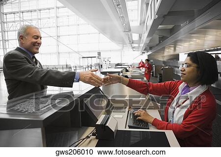 Side profile of a businessman shaking hands with an airline check-in attendant and smiling View Large Photo Image Stock Image - Side profile of a businessman shaking hands with an airline check-in attendant and smiling. Fotosearch