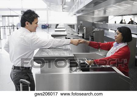 Side profile of a businessman shaking hands with an airline check-in attendant View Large Photo Image Stock Photo - Side profile of a businessman shaking hands with an airline check-in attendant. Fotosearch