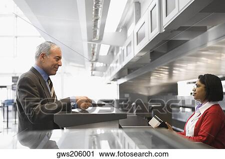 Side profile of a businessman standing at a ticket counter in an airport View Large Photo Image Stock Image - Side profile of a businessman standing at a ticket counter in an airport. Fotosearch