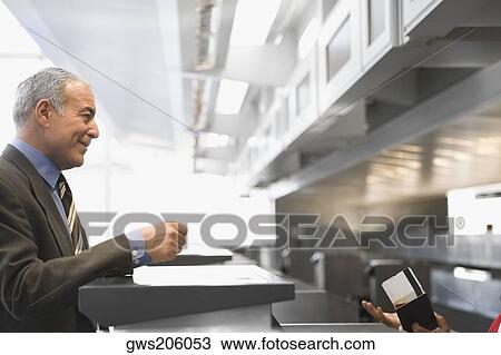 Side profile of a businessman standing at a ticket counter in an airport View Large Photo Image Stock Image - Side profile of a businessman standing at a ticket counter in an airport. Fotosearch