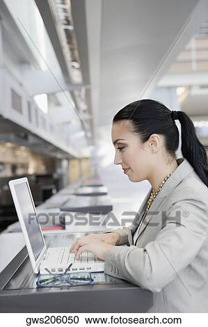 Side profile of a businesswoman using a laptop at an airport View Large Photo Image Stock Image - Side profile of a businesswoman using a laptop at an airport. Fotosearch