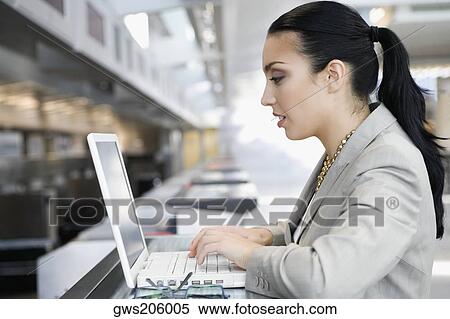 Side profile of a businesswoman using a laptop at an airport View Large Photo Image Stock Photography - Side profile of a businesswoman using a laptop at an airport. Fotosearch