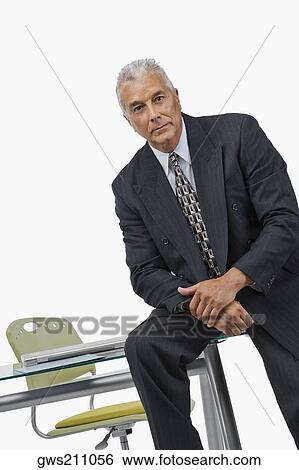 Portrait of a businessman sitting on a desk in an office View Large Photo Image Stock Photograph - Portrait of a businessman sitting on a desk in an office. Fotosearch
