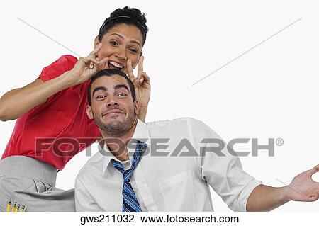 Portrait of a businesswoman gesturing behind a businessman and smiling View Large Photo Image Stock Image - Portrait of a businesswoman gesturing behind a businessman and smiling. Fotosearch