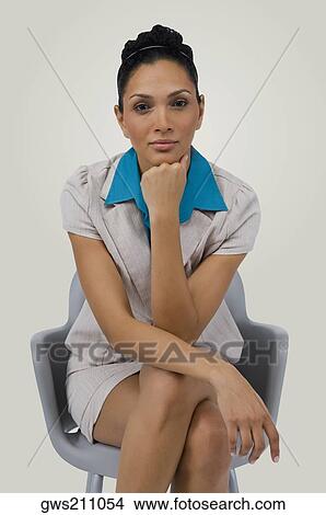 Portrait of a businesswoman sitting on a chair with her hand on her chin View Large Photo Image Picture - Portrait of a businesswoman sitting on a chair with her hand on her chin. Fotosearch
