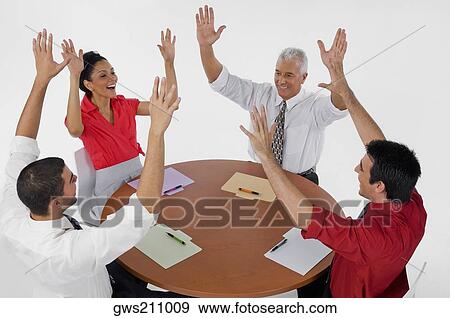 Three businessmen and a businesswoman smiling with their arms raised in a meeting View Large Photo Image Stock Photo - Three businessmen and a businesswoman smiling with their arms raised in a meeting. Fotosearch