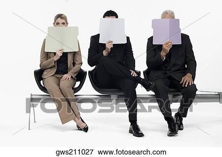 Stock Photo - Two businessmen and a businesswoman holding files in front of their faces. Fotosearch