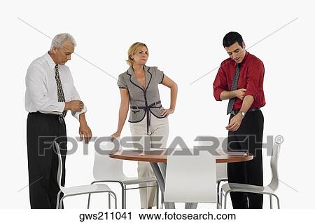 Two businessmen folding their shirt sleeves with a businesswoman standing beside them View Large Photo Image Stock Image - Two businessmen folding their shirt sleeves with a businesswoman standing beside them. Fotosearch