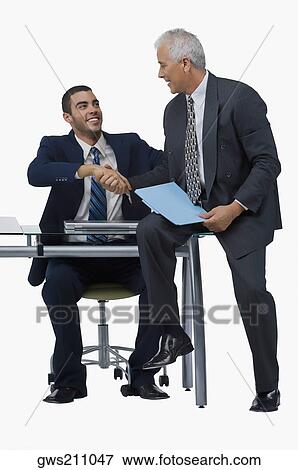 Two businessmen shaking hands and looking at each other View Large Photo Image Stock Photo - Two businessmen shaking hands and looking at each other. Fotosearch