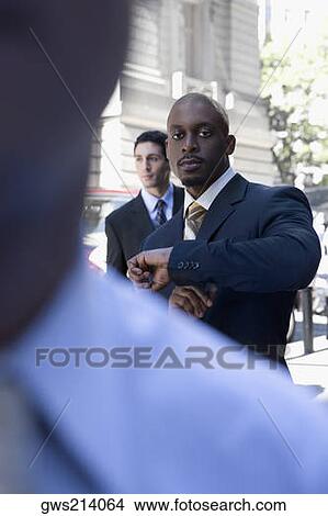 Businessman checking the time and looking serious View Large Photo Image Picture - Businessman checking the time and looking serious. Fotosearch