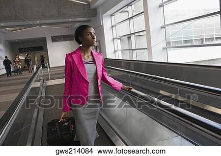 Businesswoman standing on an escalator at an airport View Large Photo Image Picture - Businesswoman standing on an escalator at an airport. Fotosearch