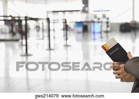 Close-up of a person's hand holding a passport with an airplane ticket View Large Photo Image Stock Photo - Close-up of a person's hand holding a passport with an airplane ticket. Fotosearch
