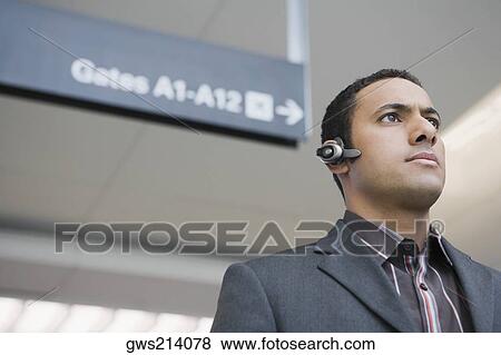 Low angle view of a businessman wearing a hands free device at an airport View Large Photo Image Stock Photo - Low angle view of a businessman wearing a hands free device at an airport. Fotosearch