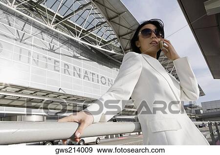 Low angle view of a businesswoman talking on a mobile phone outside an airport View Large Photo Image Stock Photo - Low angle view of a businesswoman talking on a mobile phone outside an airport. Fotosearch