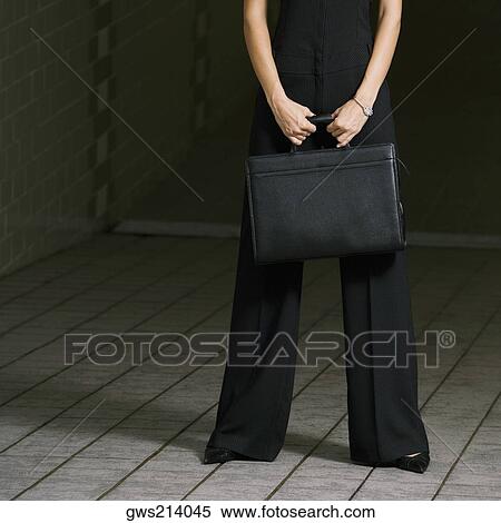 Stock Photography - Low section view of a businesswoman holding a briefcase. Fotosearch