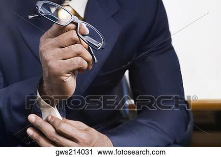 Mid section view of a businessman holding eyeglasses View Large Photo Image Stock Image - Mid section view of a businessman holding eyeglasses. Fotosearch