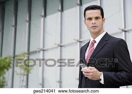 Stock Image - Portrait of a businessman holding a mobile phone. Fotosearch