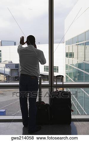 Rear view of a businessman standing with her luggage at an airport View Large Photo Image Stock Photo - Rear view of a businessman standing with her luggage at an airport. Fotosearch