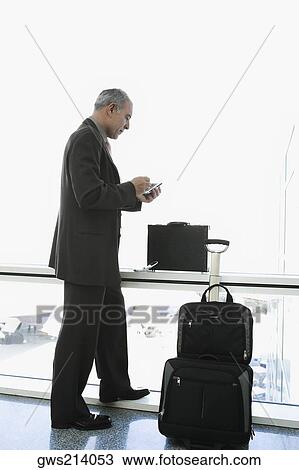 Side profile of a businessman using a palmtop in the waiting room of an airport View Large Photo Image Stock Image - Side profile of a businessman using a palmtop in the waiting room of an airport. Fotosearch