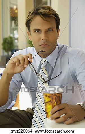 Businessman sitting in a restaurant and holding a disposable cup View Large Photo Image Picture - Businessman sitting in a restaurant and holding a disposable cup. Fotosearch