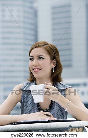Stock Photograph - Close-up of a businesswoman drinking coffee at a sidewalk cafe. Fotosearch