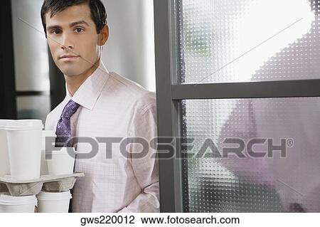 Stock Image - Portrait of a businessman holding disposable cups. Fotosearch