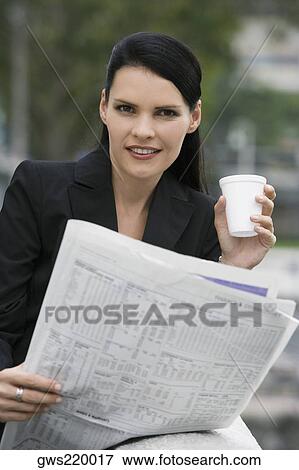Stock Photo - Portrait of a businesswoman holding a disposable cup and a newspaper. Fotosearch
