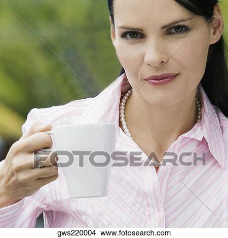 Picture - Portrait of a mid adult woman holding a cup of coffee and smiling. Fotosearch