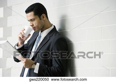 Stock Image - Side profile of a businessman reading a newspaper. Fotosearch