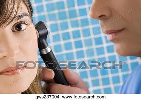 Close-up of a male doctor examining a mature woman's ear View Large Photo Image Picture - Close-up of a male doctor examining a mature woman's ear. Fotosearch