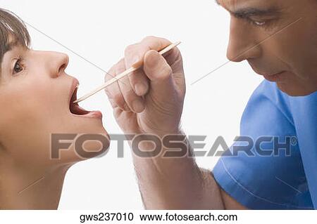 Stock Image - Close-up of a male doctor examining a mature woman's mouth. Fotosearch