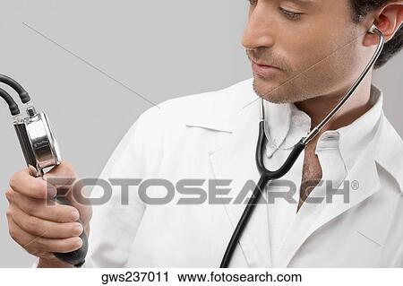 Close-up of a male doctor holding a blood pressure gauge View Large Photo Image Stock Image - Close-up of a male doctor holding a blood pressure gauge. Fotosearch