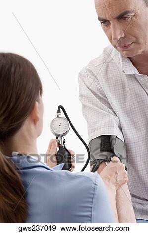 Female doctor checking blood pressure of a mature man View Large Photo Image Stock Photo - Female doctor checking blood pressure of a mature man. Fotosearch