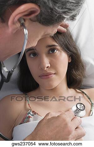 High angle view of a male doctor examining a young woman View Large Photo Image Picture - High angle view of a male doctor examining a young woman. Fotosearch