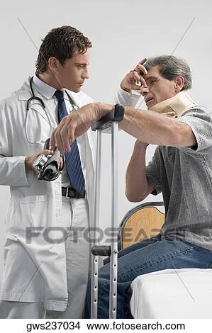 Picture - Male doctor examining a patient in a hospital. Fotosearch