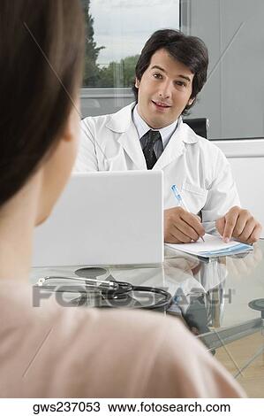 Male doctor sitting with a patient in a clinic View Large Photo Image Stock Image - Male doctor sitting with a patient in a clinic. Fotosearch