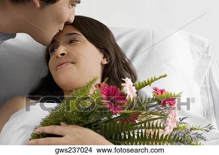 Mid adult man kissing a young woman in a hospital ward View Large Photo Image Picture - Mid adult man kissing a young woman in a hospital ward. Fotosearch