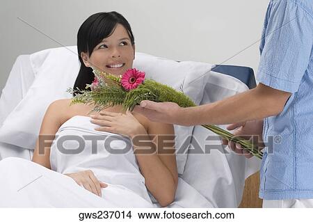 Mid section view of a man giving bouquet of flowers to a patient lying on the bed View Large Photo Image Picture - Mid section view of a man giving bouquet of flowers to a patient lying on the bed. Fotosearch
