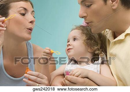 Close-up of a mid adult couple looking at their daughter View Large Photo Image Stock Photo - Close-up of a mid adult couple looking at their daughter. Fotosearch
