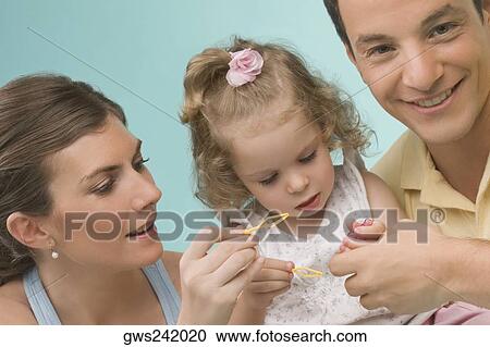 Close-up of a mid adult couple playing with their daughter View Large Photo Image Stock Image - Close-up of a mid adult couple playing with their daughter. Fotosearch