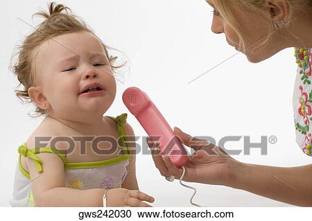 Stock Image - Close-up of a mid adult woman giving the receiver of a toy phone to her daughter. Fotosearch
